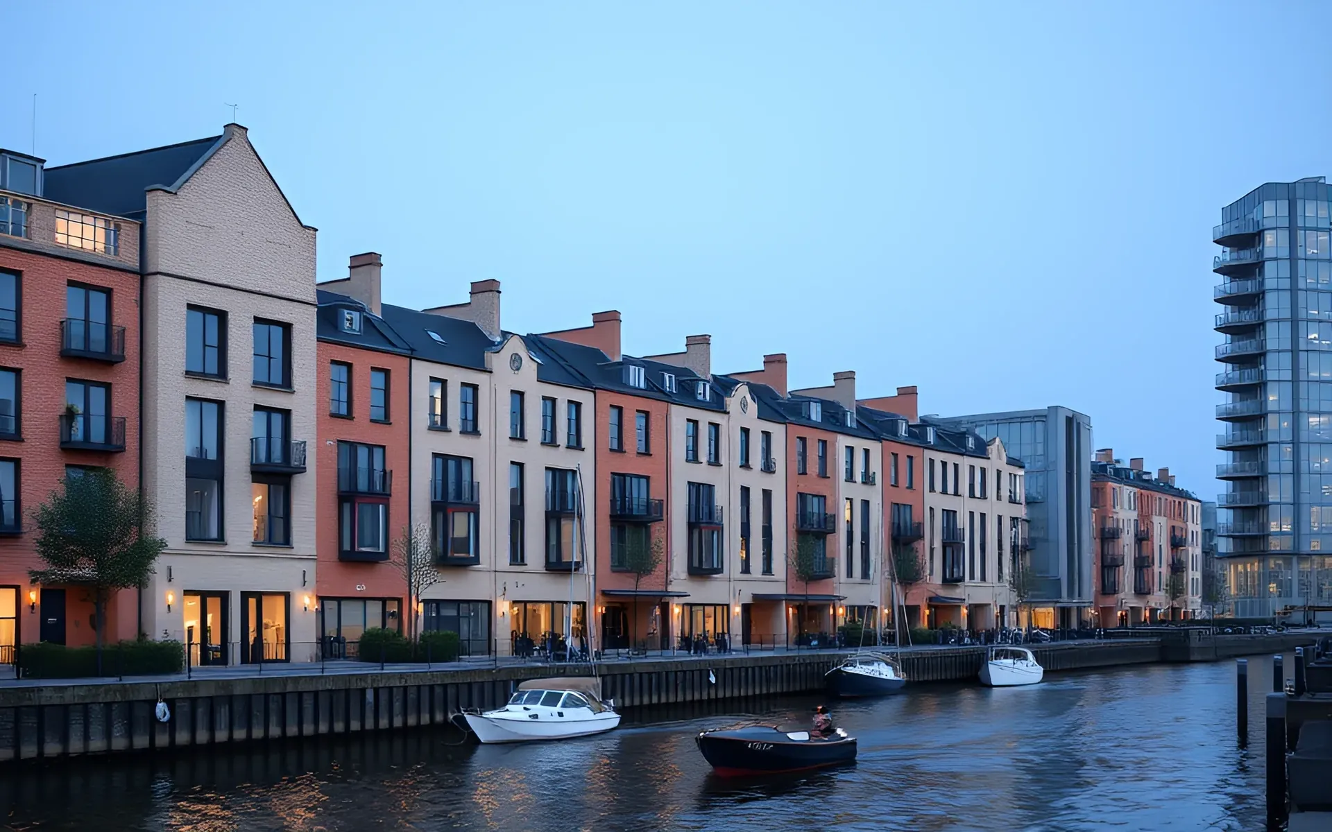 A row of narrow brick and glass townhouses on a harbour quay at dusk